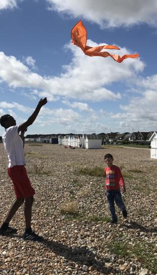 Man flying a kite on beach with a child