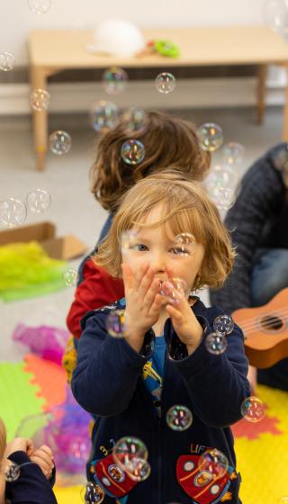 Children at a Dads & Toddler Group blowing bubbles