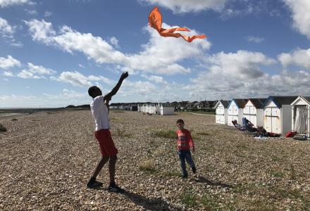 Man flying a kite on beach with a child