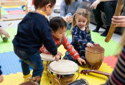 Three toddlers playing with drums