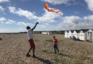 Man flying a kite on beach with a child