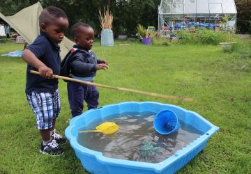 Two small children by a paddling pool