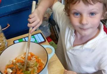 A small child stirring a cooking pot