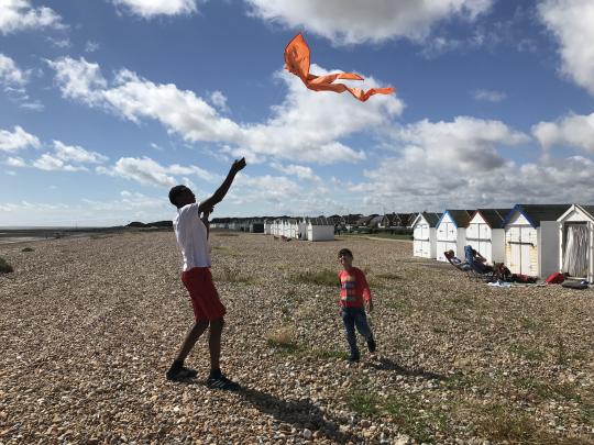 Man flying a kite on beach with a child