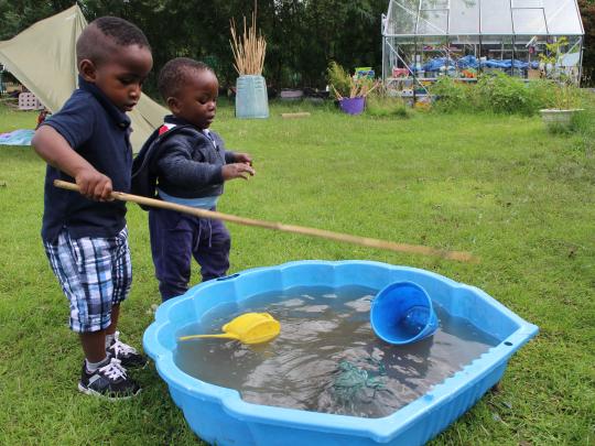 Two small children by a paddling pool