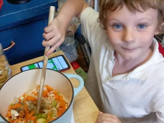 A small child stirring a cooking pot